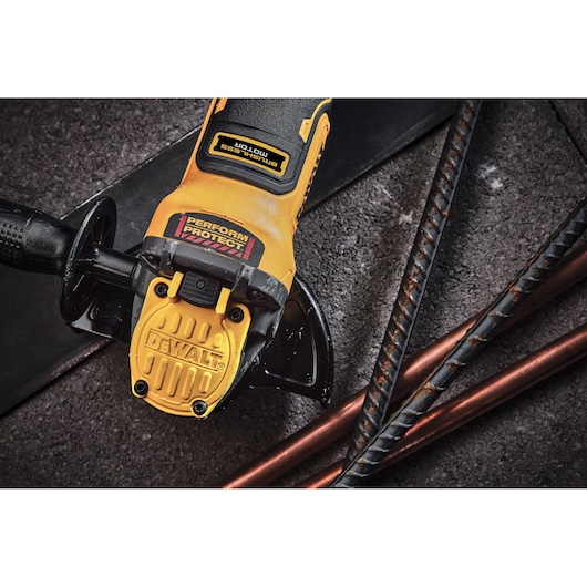 A close-up view of a yellow DEWALT brushless motor angle grinder, shown resting on a concrete surface near metal rods.
