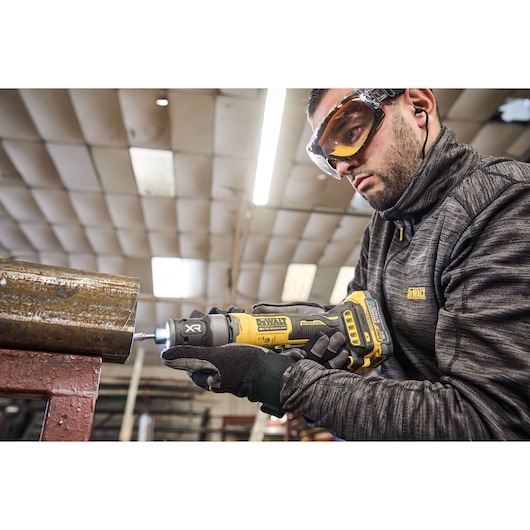 DEWALT DCG420N-XJ, DCG420N tool in use on metal pipe. User in DEWALT gear. Photography category.