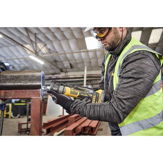Worker uses DEWALT DCG420N-XJ and DCG420N tool on metal pipe in industrial setting.