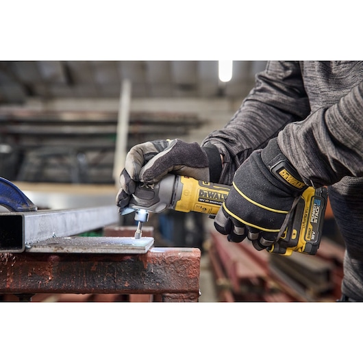 DEWALT DCG421N-XJ, DCG421N tool in use by gloved hands polishing metal, in workshop. Photography category.
