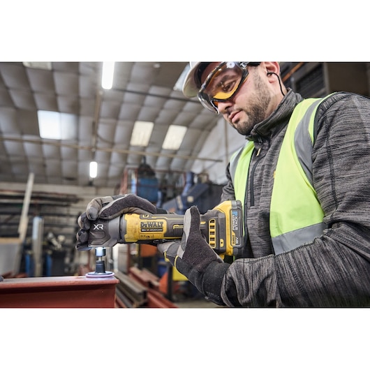 DEWALT DCG421N-XJ, DCG421N grinder in use for industrial metalwork. Photography category, worker’s face blurred.