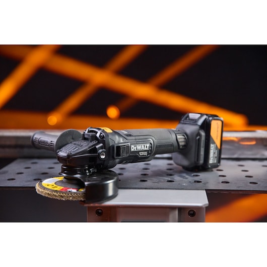 DEWALT cordless grinder, DCG45MP2T-QW and DCG45MP2T SKUs, on a metal table with orange background.