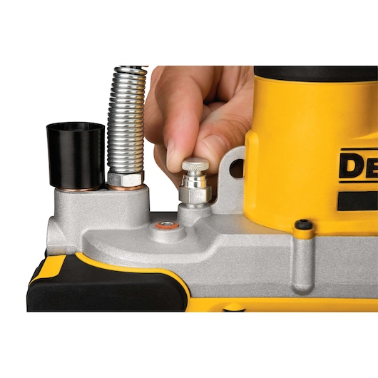 Close-up of a hand adjusting a metal knob on a yellow and silver DEWALT tool, showing detailed components and part of the