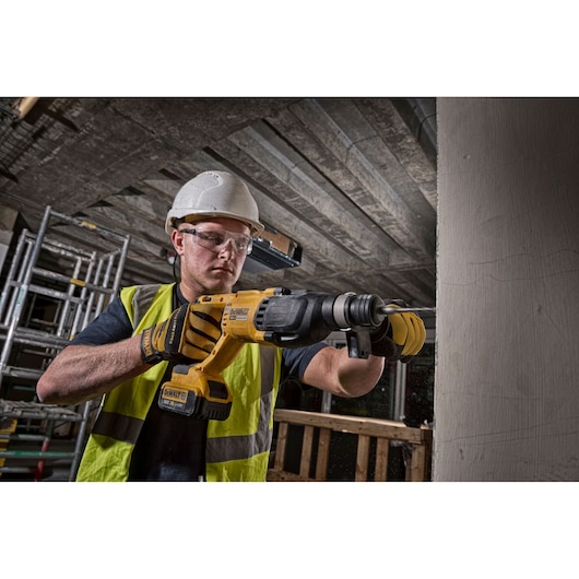 Worker uses DEWALT DCH133M1-QW, DCH133M1 rotary hammer drill at construction site. Photography product category.