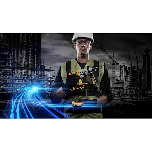 Worker holds a DEWALT cordless drill at a construction site with city buildings and blue light streaks in background.