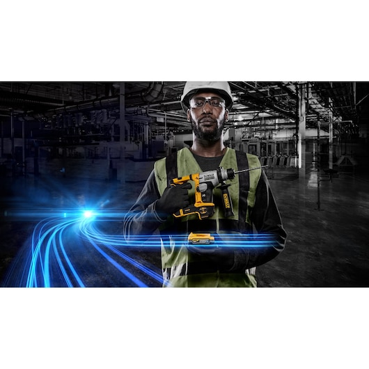 Worker holding a DEWALT cordless drill with light streaks in an industrial setting. Face is blurred for privacy.