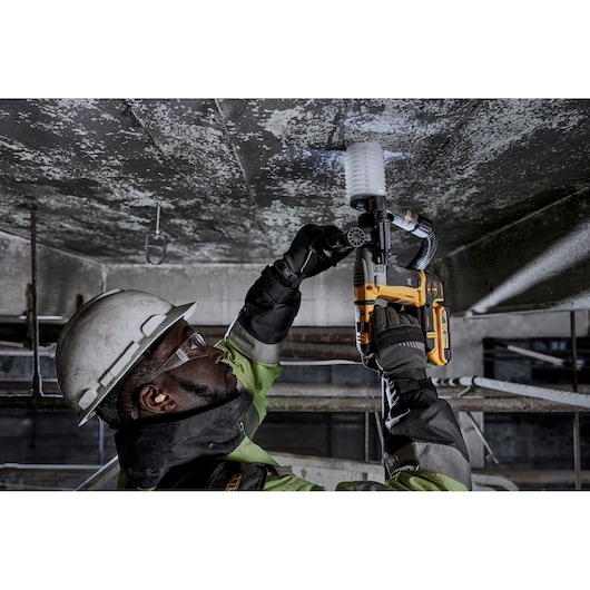 Worker uses DEWALT DCH172NT-XJ, DCH172NT on ceiling. Industrial setting, safety gear worn.