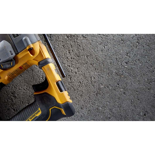 Close-up of a yellow DEWALT power tool resting on a rough concrete surface.
