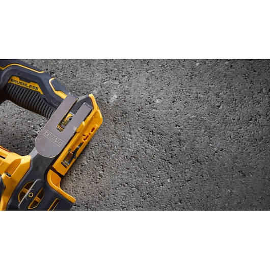 Close-up of a yellow DEWALT brushless tool on a rough concrete surface.