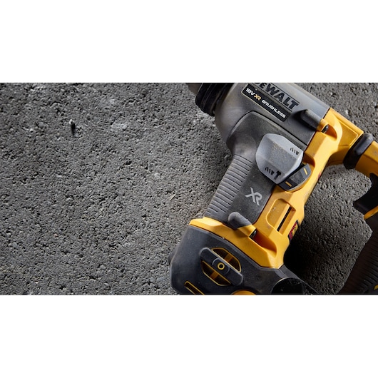 Close-up of a DEWALT 18V XR brushless cordless drill on rough concrete surface.