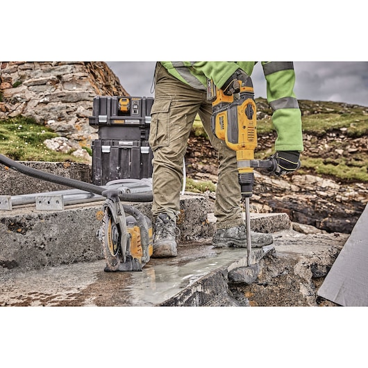 Worker uses DEWALT power tools for breaking and cutting concrete on an outdoor construction site.
