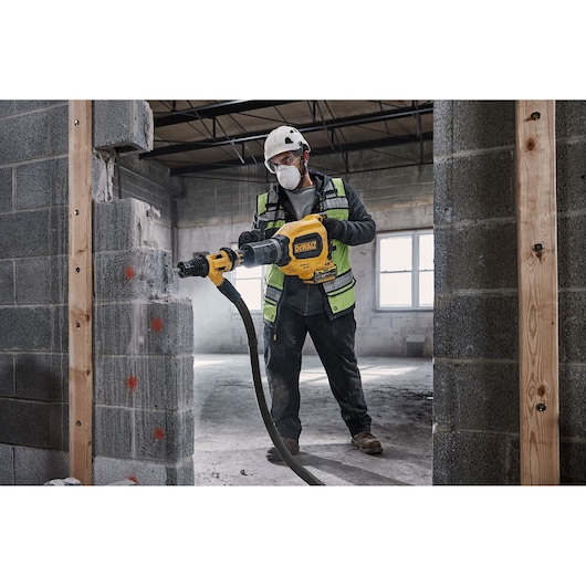 Worker uses DEWALT DCH911NK rotary hammer to drill a concrete wall at a construction site.