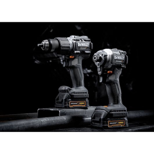 Two DEWALT cordless power tools, a drill driver and an impact driver, both with batteries attached, displayed on a dark industrial surface with a black background.