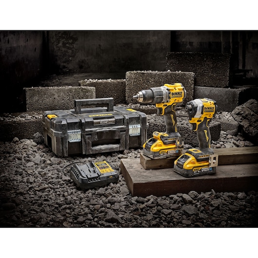 DEWALT tool kit with two power tools, charger, and case placed on construction site rubble.