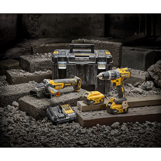 DEWALT tool kit with drill, grinder, batteries, charger and case on a construction site.