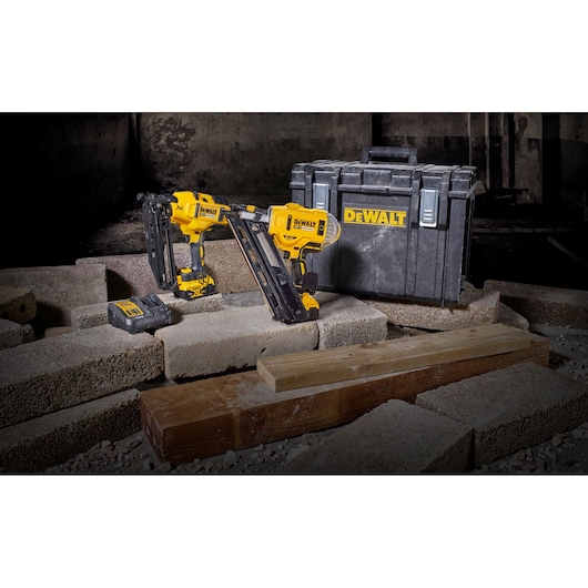 DEWALT cordless nail guns with battery and case on construction site bricks and wood.