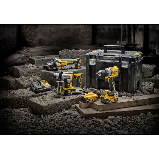 DEWALT tool kit with power tools, batteries, charger, and case displayed on concrete blocks.