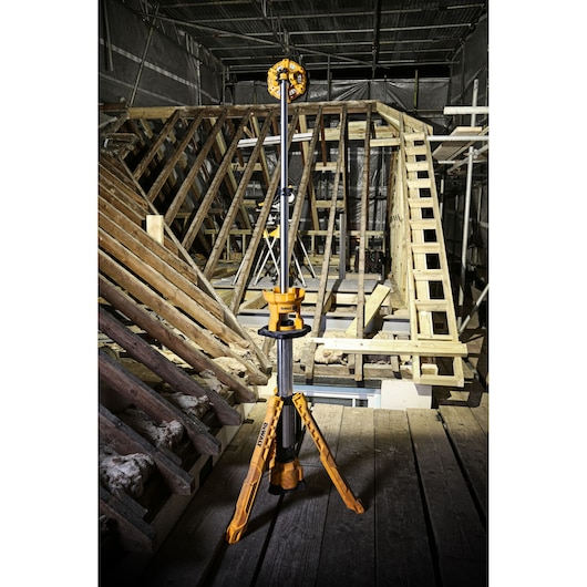 DEWALT DCL079 tripod work light on a construction site with wood beams and scaffolding in the background.