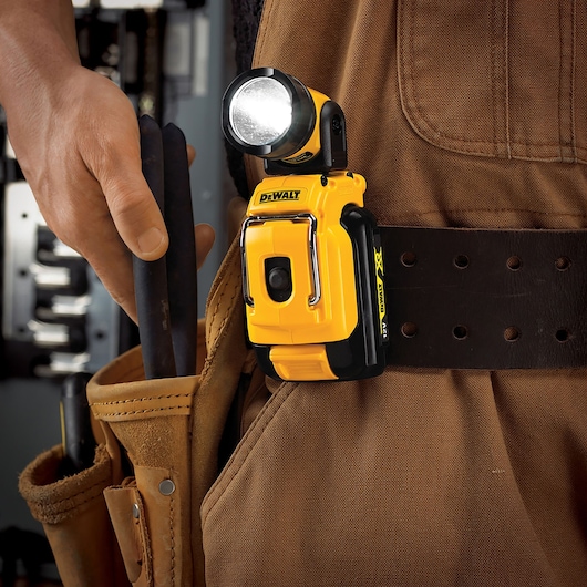 DEWALT DCL510N LED work light attached to a tool belt worn by a person in a brown work outfit.