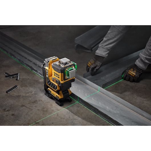 DEWALT laser level projects green lines onto metal tracks for alignment during construction work.