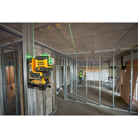 DEWALT green laser level mounted on metal stud for construction alignment in an unfinished building.