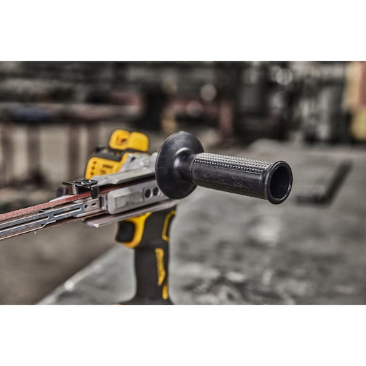 DEWALT DCM200NT belt sander tool with handle shown close-up on a workshop table.