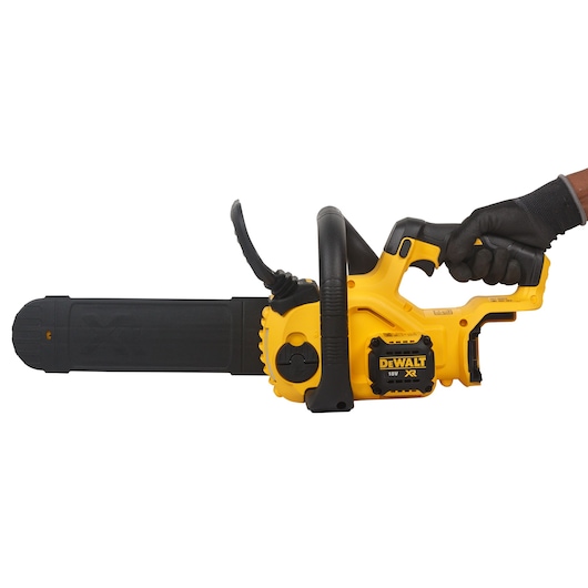 A yellow and black DEWALT 18V XR cordless chainsaw with a protective bar cover, being held by a gloved hand.
