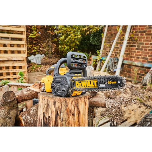 DEWALT cordless chainsaw placed on a tree stump outdoors. Chain size is 30 cm.