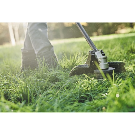 DEWALT DCMASST1N, DCZ65713X1-XE, DCMASST1N-XJ string trimmer used on grass outdoors.