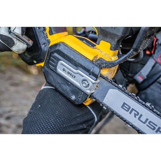 Close-up of a DEWALT chainsaw in use, showing part of the chain and the DEWALT branding on the tool.