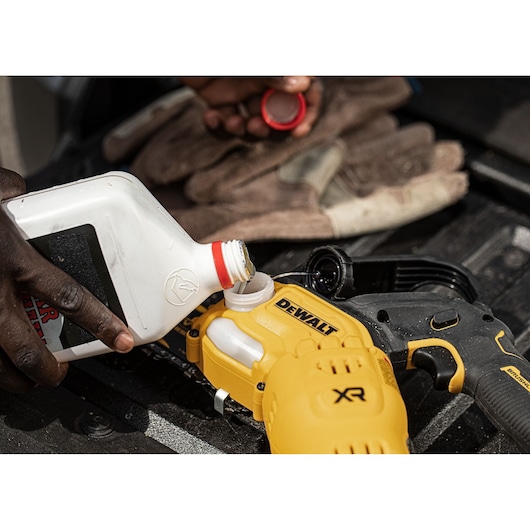 Person pours liquid into a DEWALT XR tool, with gloves and a bottle visible in the scene.