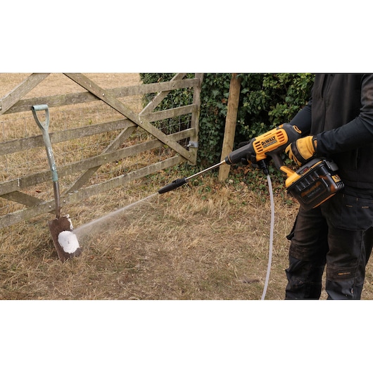 DEWALT DCMPW1000N, DCMPW1000N-XJ in use cleaning a shovel outdoors. Photography product category.