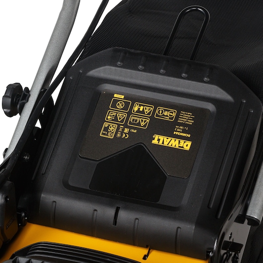 Close-up of DEWALT DCMW564N lawn mower top with warning labels and brand logo visible.