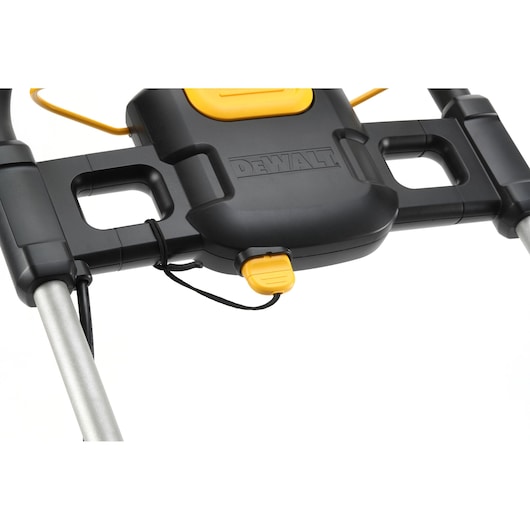 Close-up of the DEWALT DCMW564N lawn mower handle with a yellow button and brand logo visible.