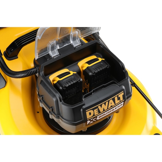 Close-up of DEWALT brushless lawn mower battery compartment with two yellow-black batteries.