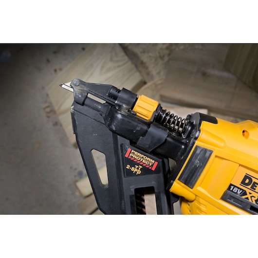 Close-up of a DEWALT 18V XR tool with a pointed metal tip, black and yellow, on a wood surface.