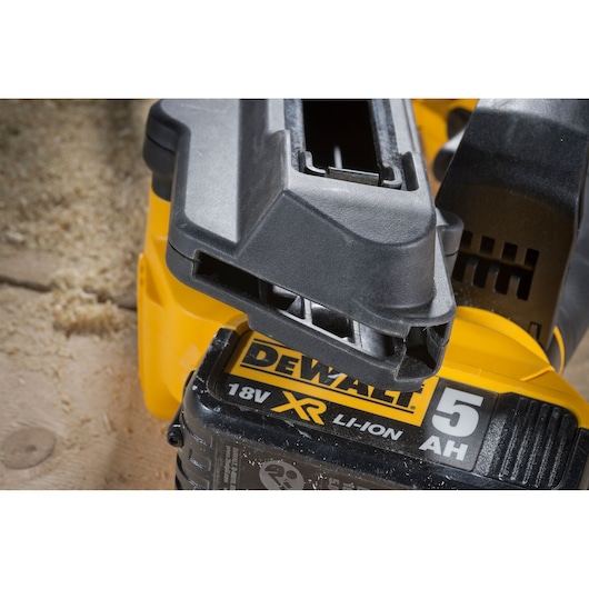 Close-up of a DEWALT 18V XR Li-Ion 5AH battery attached to a yellow power tool on a wooden surface.