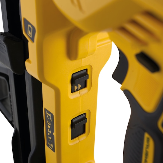 Close-up of yellow DEWALT tool with two black switches and battery symbol, part of handle visible.