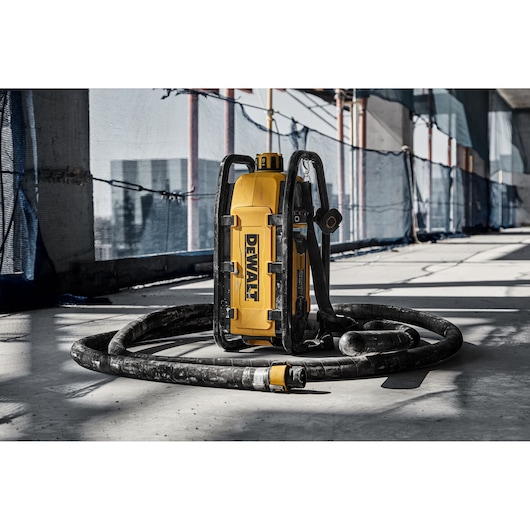 DEWALT DCPS320N tool with hose is placed on a construction site floor in sunlight.