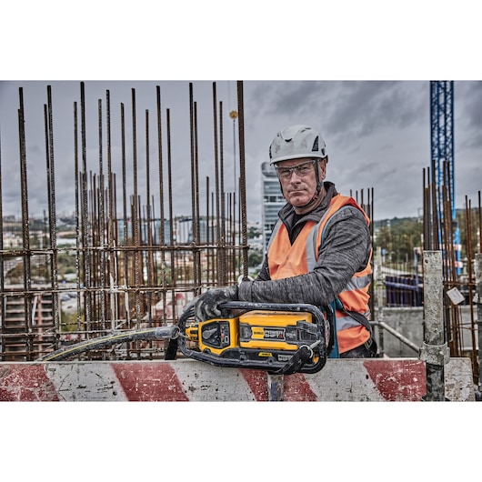 Worker with DEWALT Power Shift tool on construction site, wearing safety gear, rebar in background.