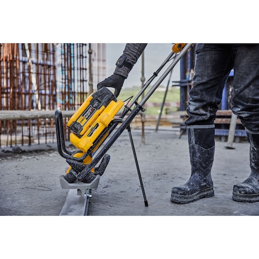 DEWALT power tool used outdoors by worker in safety gear at construction site.