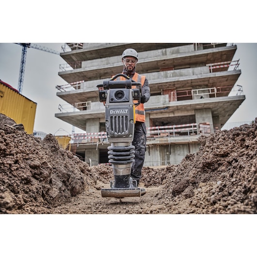 DEWALT compactor in use on a construction site, operated by a worker in safety gear.