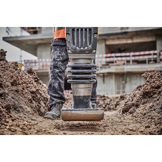 Close-up of a DEWALT compactor in use on a construction site, pressing soil for groundwork.