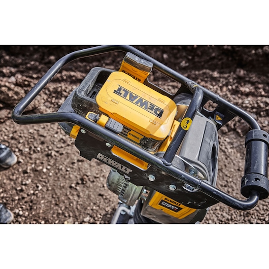 DEWALT industrial tool with yellow casing and handle, photographed outdoors on a dirt surface.