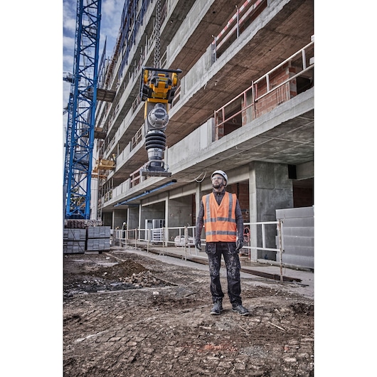 DEWALT DCPS660N tool suspended at construction site, worker in safety gear standing on ground.