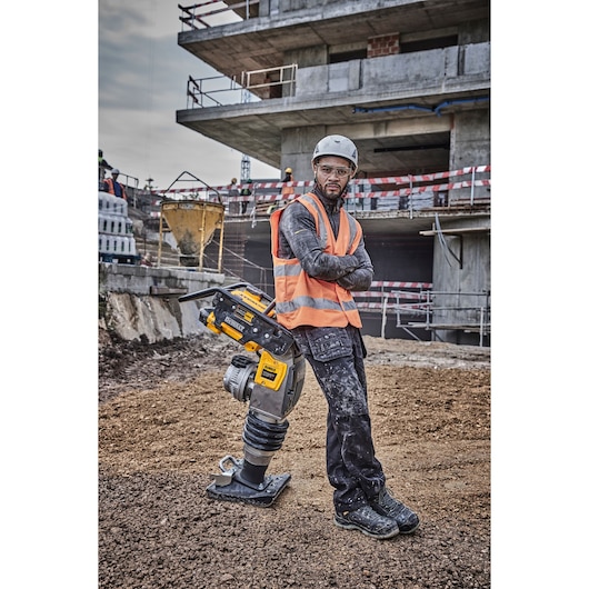 DEWALT DCPS660N tool beside a construction worker in safety gear at a building site.