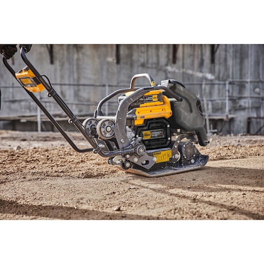 DEWALT plate compactor DCPS7154N on a construction site smoothing soil with operator partially visible.