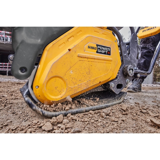 DEWALT POWER SHIFT compactor working on soil at a construction site, close-up of yellow machine in use.