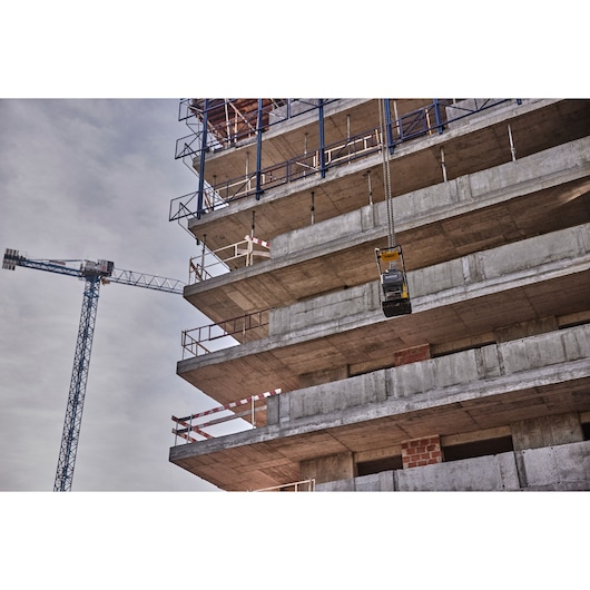 DEWALT tool hoisted by crane at a concrete building construction site, with unfinished floors visible.