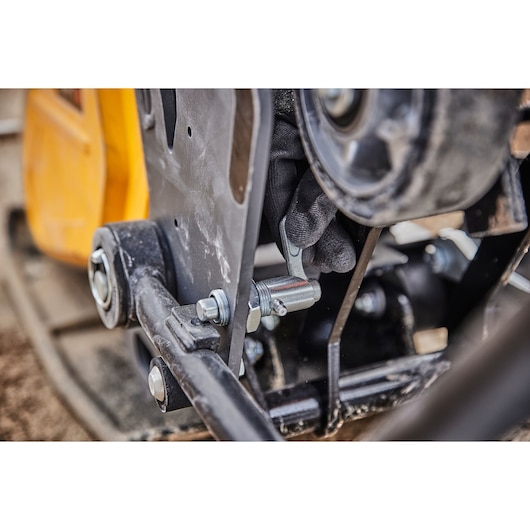 Close-up of a DEWALT tool mechanism with a gloved hand adjusting a metal bolt or component.